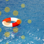 A red and white life preserver floats on the surface of the blue ocean.